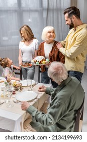 Senior Woman Holding Easter Cake While Serving Table For Family Easter Dinner