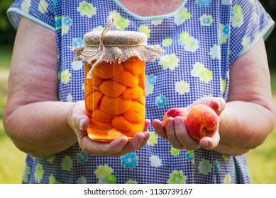 Senior woman holding glass jar of preserved apricots and ripe apricot in her hands. Old female cook in garden. - Powered by Shutterstock