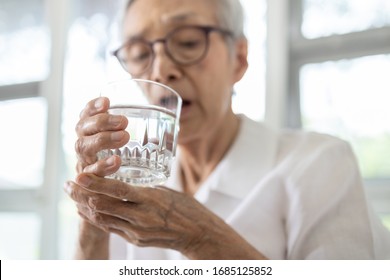Senior woman holding glass of water,hand shaking while drinking water,elderly patient with hands tremor uncontrolled body tremors,symptom of essential tremor,parkinson's disease,neurological disorders - Shutterstock ID 1685125852