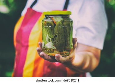 Senior woman holding a jar of pickles in the garden. Homemade pickled cucumbers in a glass jar. Preserving jar of gherkins with mustard seeds and dill. - Powered by Shutterstock