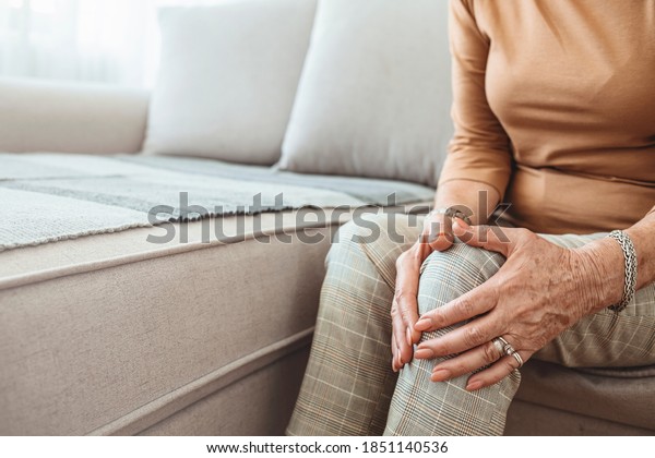 Senior\
woman holding the knee with pain. Old age, health problem and\
people concept - senior woman suffering from pain in leg at home.\
Elderly woman suffering from pain in knee at\
home