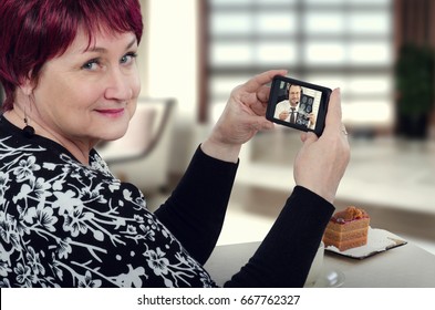 Senior Woman Holding Mobile Phone By Hands. On The Screen There Is Virtual Doctor Attentively Reviewing Brain X-ray Results. Patient Contacts Physician Via Mobile Phone With Telemedicine Application
