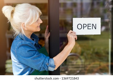 Senior woman holding open sign in organic produce shop - Powered by Shutterstock