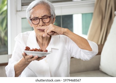 Senior Woman Holding Plate Of Bad Spoiled Or Expired Food In Her Hand,rotten Food,emitting A Fetid Smell Or Strong-smelling Food,disgusted Old Elderly Cover Nose With Her Finger,diet,nutrition Concept