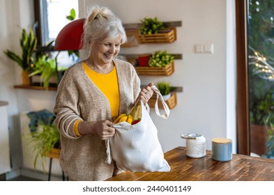 Senior woman holding reusable bag with groceries in kitchen
 - Powered by Shutterstock