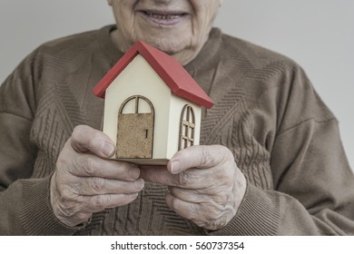 A Senior woman holding small wooden house