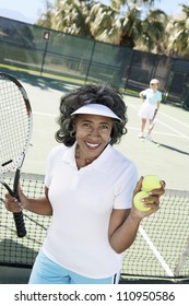 Senior Woman Holding Tennis Racquet And Ball Against Sky