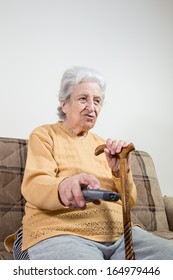 a senior woman holding (using) remote control