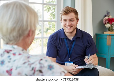Senior Woman At Home With Male Care Worker Making Notes