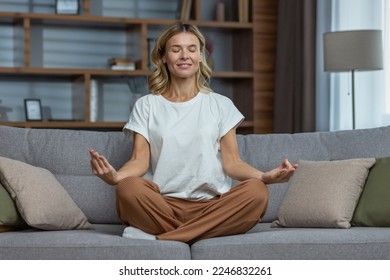 Senior woman at home resting meditating with eyes closed sitting on sofa in living room, housewife mature blonde in lotus pose smiling. - Powered by Shutterstock