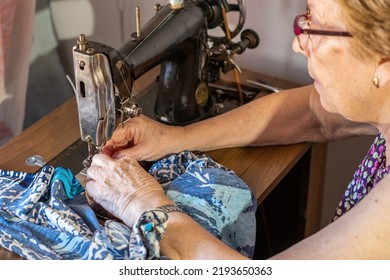 Senior Woman At Home, Sitting Sewing On A Sewing Machine.