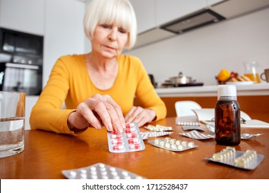 Senior woman at home sitting at table and kitchen at home taking blister pack with pills feeling unwell close-up blurred background concerned - Powered by Shutterstock