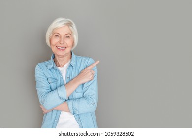 Senior Woman In Jeans Jacket Studio Isolated On Grey Wall Pointing Aside Creative Idea