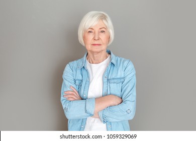 Senior Woman In Jeans Jacket Studio Isolated On Grey Wall Serious