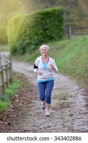 Senior Woman Jogging Outside With Earphones On