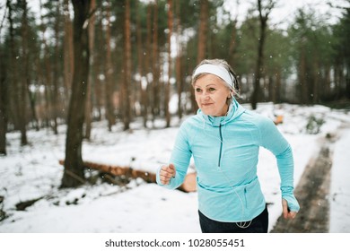 Senior Woman Jogging In Winter Nature.