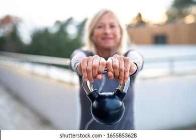 A senior woman with kettlebell outdoors doing exercise. - Powered by Shutterstock