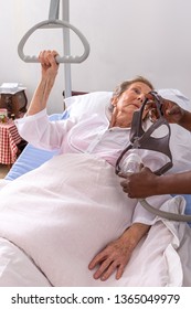 Senior Woman Lay In Bed At Home Nurse Showing Her CPAP Mask, Sleep Apnea Therapy.