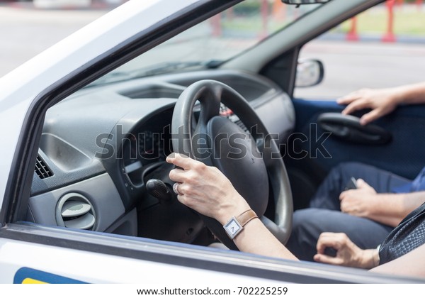Senior woman learning to drive a car with a\
driving instructor