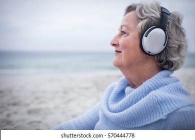 Senior woman listening to music on headphone at beach - Powered by Shutterstock