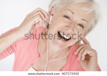A senior woman listening to music on an mp3 player, laughing