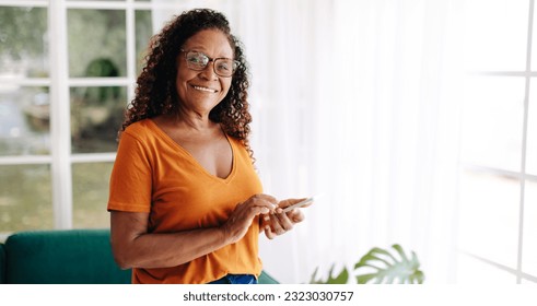 Senior woman living alone uses her smartphone to stay connected and feel secure, with the ability to make calls, send texts, and access the friendly online communities of fellow senior citizens. - Powered by Shutterstock