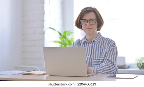 Senior Woman Looking At Camera While Using Laptop