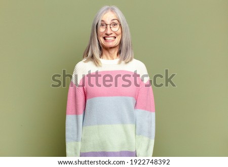 senior woman looking happy and goofy with a broad, fun, loony smile and eyes wide open