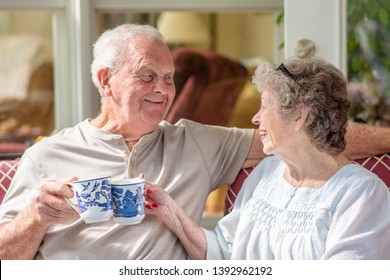 Senior woman looking at her husband. A beautiful senior couple in their seventies talks and laughs while they enjoy coffee or tea on their sunny porch one morning. - Powered by Shutterstock