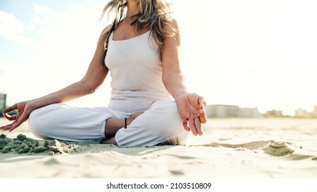 Senior Woman In Lotus Pose Sitting On The Sand - Yoga At Beach - Calm And Meditation Concept