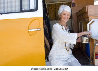 Senior Woman Making Tea In Camper Van, Smiling, Portrait