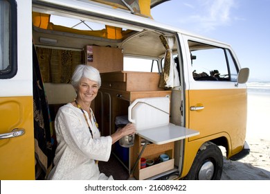 Senior Woman Making Tea In Camper Van On Beach, Smiling, Portrait, Close-up