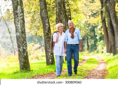 Senior Woman And Man, A Couple, Embracing Each Other Having Walk In The Fall Forest