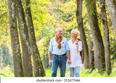 Senior Woman And Man, A Couple, Embracing Each Other Having Walk In The Fall Forest