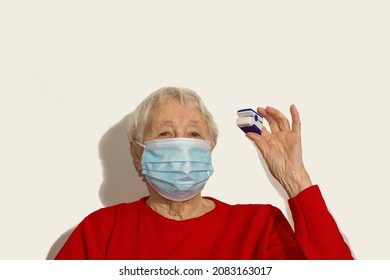 Senior Woman In Mask Using Pulse Oximeter At Home To Test Oxygen Level In Blood