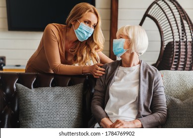 Senior woman in medical mask with social worker visiting her at home - Shutterstock ID 1784769902