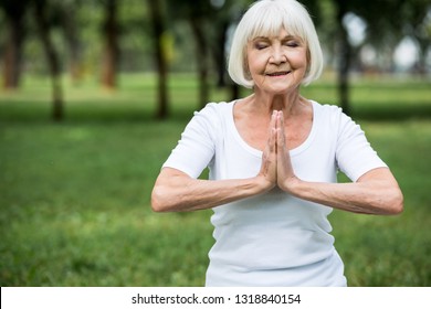 Senior Woman In Meditation Sukhasana Pose With Folded Hands