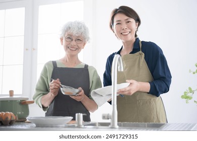 Senior woman and middle-aged woman in the kitchen. Holding plates in their hands, looking at the camera and smiling. Images of cooking classes, wives and mother-in-laws, household chores. - Powered by Shutterstock