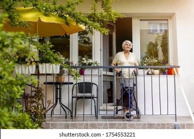 Senior woman with mobility walker standing on her balcony
