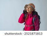 Senior woman in mountaineering clothes talking on her smartphone in fear