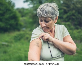 A Senior Woman In Nature Is Looking At A Bruise On Her Arm