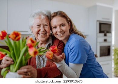 Senior woman and nurse with tulip bouquet. - Powered by Shutterstock