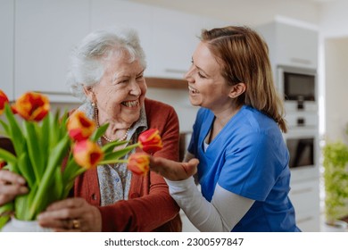 Senior woman and nurse with tulip bouquet. - Powered by Shutterstock