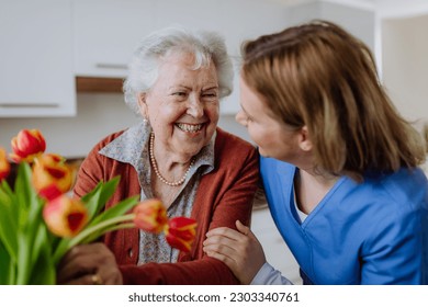 Senior woman and nurse with tulip bouquet.