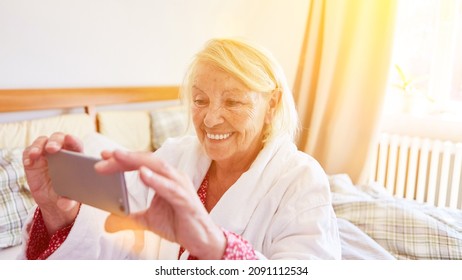 Senior Woman In Nursing Home Video Chat With Family On Smartphone With Webcam