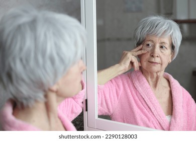 Senior woman observing her image in the mirror - Powered by Shutterstock