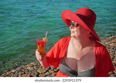 Senior woman on the beach holding a cocktail in her hands. Selective focus. Drink. Outdoors - Powered by Shutterstock