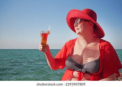 Senior woman on the beach holding a cocktail in her hands. Selective focus. Drink. Outdoors - Powered by Shutterstock