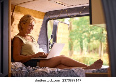 Senior Woman On Camping Trip In Countryside Working Inside RV Using Laptop - Powered by Shutterstock