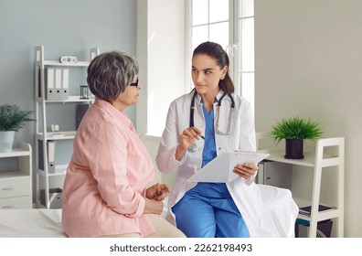 Senior woman on check up appointment with young doctor woman who writing symptoms in flipboard and listening her sitting on the couch. Checkup, prevention examination, diagnosis, medicine concept. - Powered by Shutterstock
